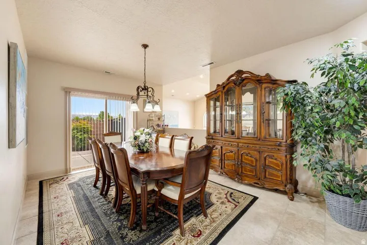 Tile flooring, sliding glass door, overhead chandelier, vaulted ceilings, neutral wall tones