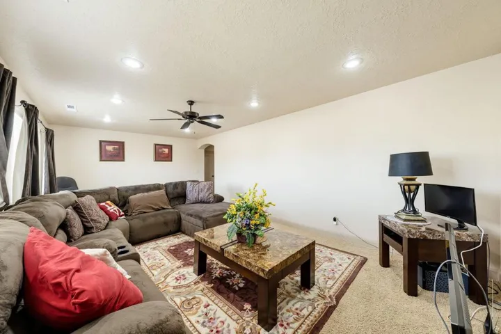 Recessed ceiling lighting, ceiling fan, neutral wall tones, and arched entryway