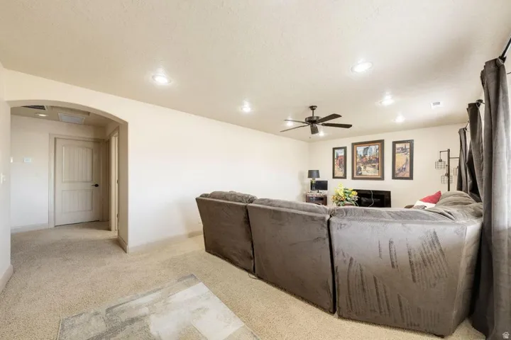 Recessed lighting, ceiling fan, arched doorway, and light-toned carpeting