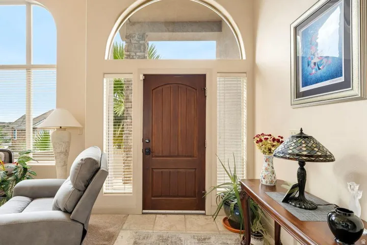 Arched entryway with a wood-paneled door, side light windows, and transom window