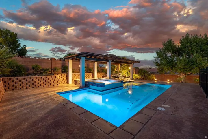 Swimming pool with integrated spa, adjacent pergola, and surrounding hardscaping