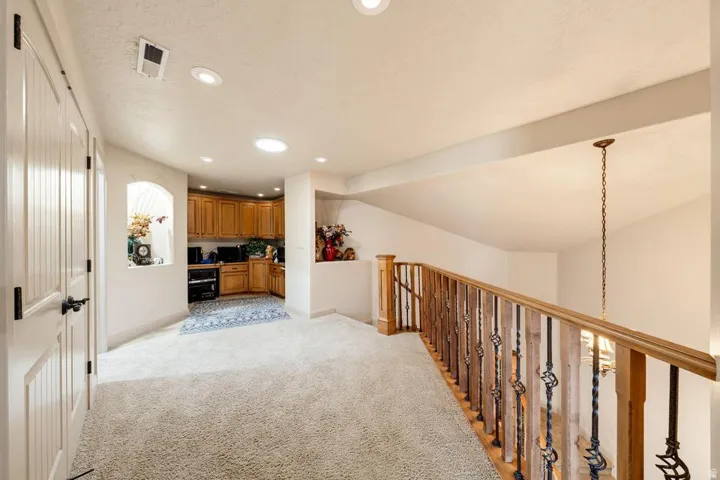Carpeted landing with a wood and wrought iron staircase railing