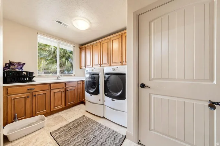 Laundry area with wood cabinetry, light-toned countertop, and tiled flooring