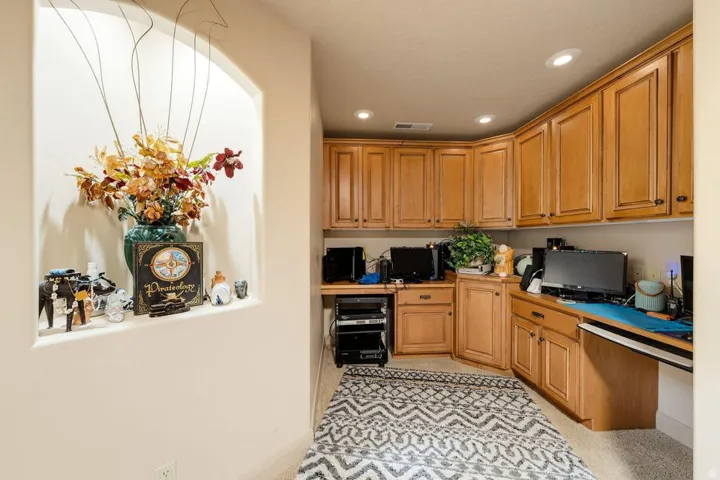 Recessed wall niche with arched top, built-in cabinetry, integrated desk space, and recessed ceiling lights