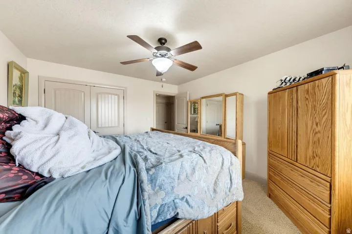 Ceiling fan with integrated lighting, wood-finish bi-fold closet doors, and light-toned wall paint