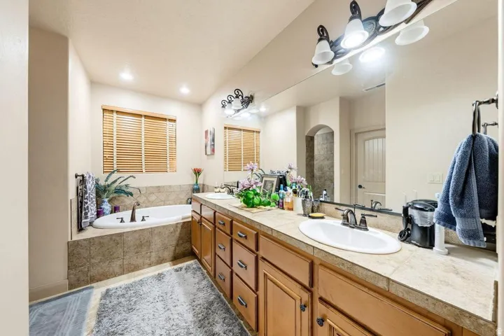 Dual vanity with undermount sinks, wood cabinetry, and a tile countertop