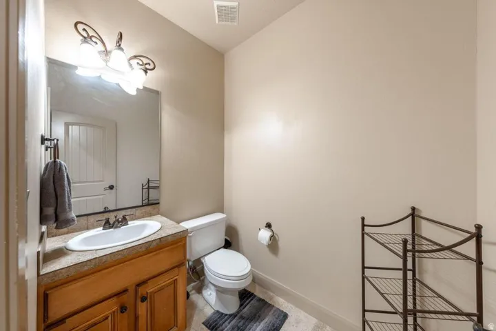 Vanity with wood-finish cabinetry, integrated sink, and mounted mirror
