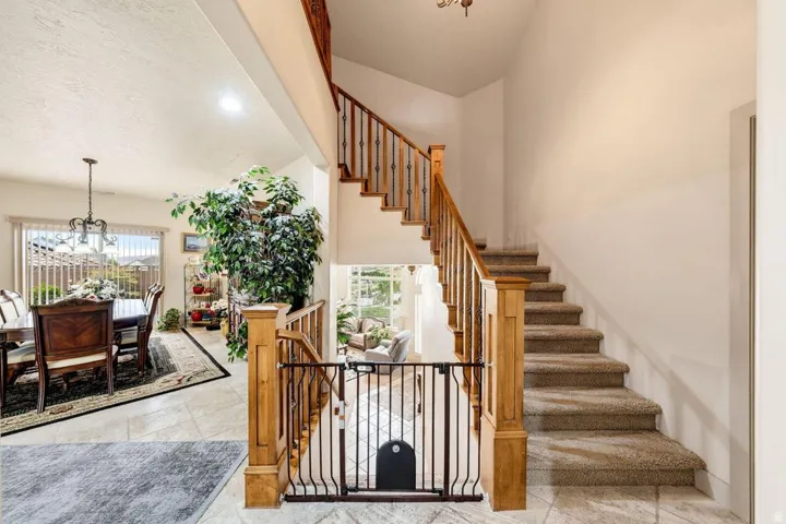 Two-story entry featuring a carpeted staircase with wood banister and wrought iron spindles