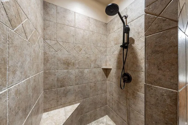 Tile shower enclosure featuring a built-in bench, recessed shelf, and matte black shower fixtures