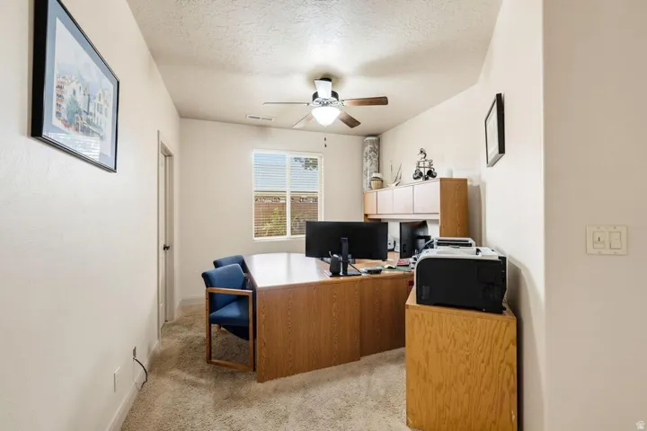 Carpeted room featuring a ceiling fan with light fixture and a window with blinds