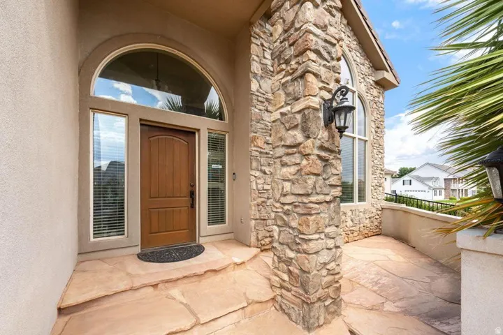 Arched entryway with a wood-panel door, sidelight windows, and an arched transom