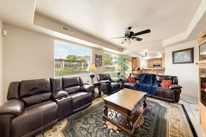 Open-concept living space with a ceiling fan, recessed lighting, and a wide window with blinds