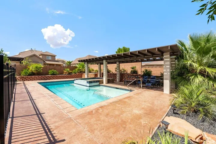 Swimming pool with an integrated spa, expansive stamped concrete decking, and a contemporary pergola