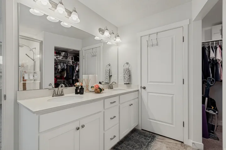 Dual vanity with integrated sinks, white cabinetry, chrome fixtures, and a framed mirror