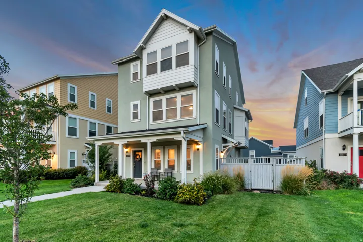 Three-story structure with a covered front porch, white trim accents, and a fenced side yard