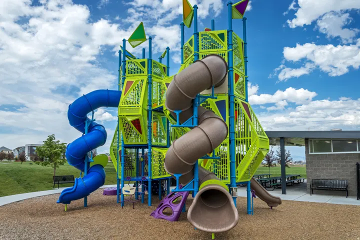 Multi-level playground structure featuring multiple slides, climbing elements, and a ground covering of wood chips