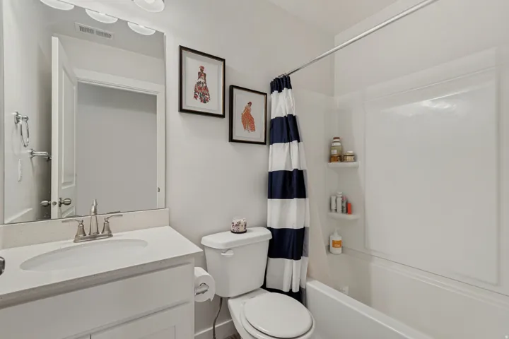 White vanity with integrated sink, brushed nickel faucet, large mirror, and overhead vanity lighting