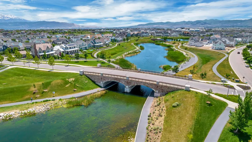 Expansive community featuring a large lake, walking paths, a stone-clad bridge, and surrounding residences