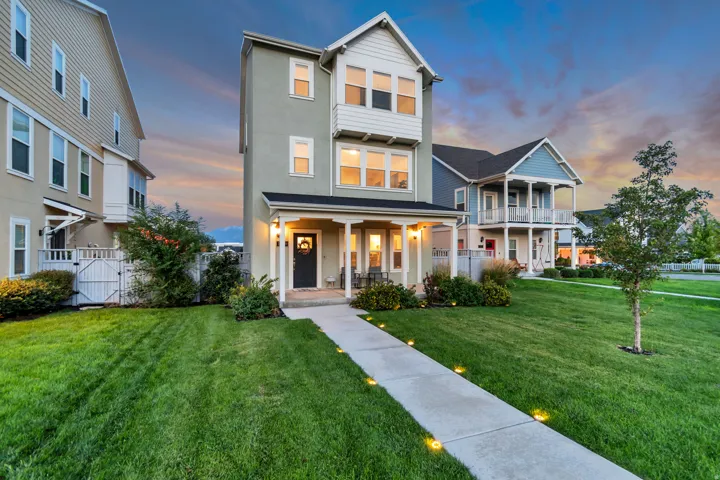 Stucco and siding exterior with multiple windows, a covered front porch, and a walkway with integrated ground lighting