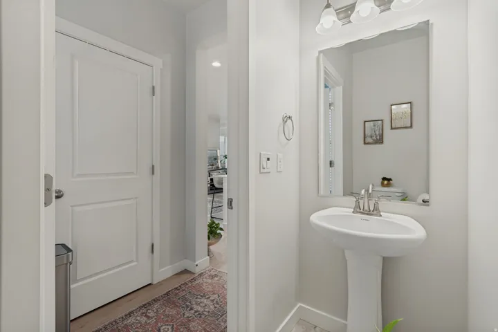 Pedestal sink with chrome faucet, large vanity mirror, and three-light fixture