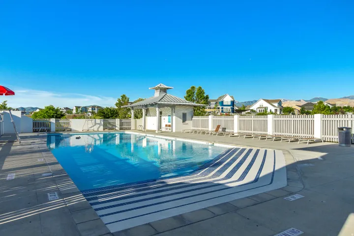 Outdoor swimming pool with built-in steps, surrounding concrete deck, and white picket fencing