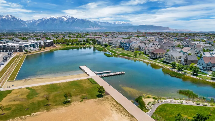 Expansive community lake with a dock, surrounded by residential properties and green spaces, with distant mountains