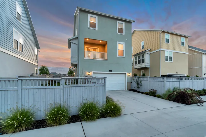 Stucco exterior with a balcony and white railing, attached garage, and a concrete driveway