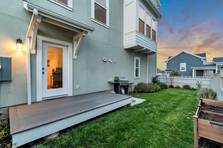 Private backyard featuring a composite deck, mature landscaping, and raised garden beds