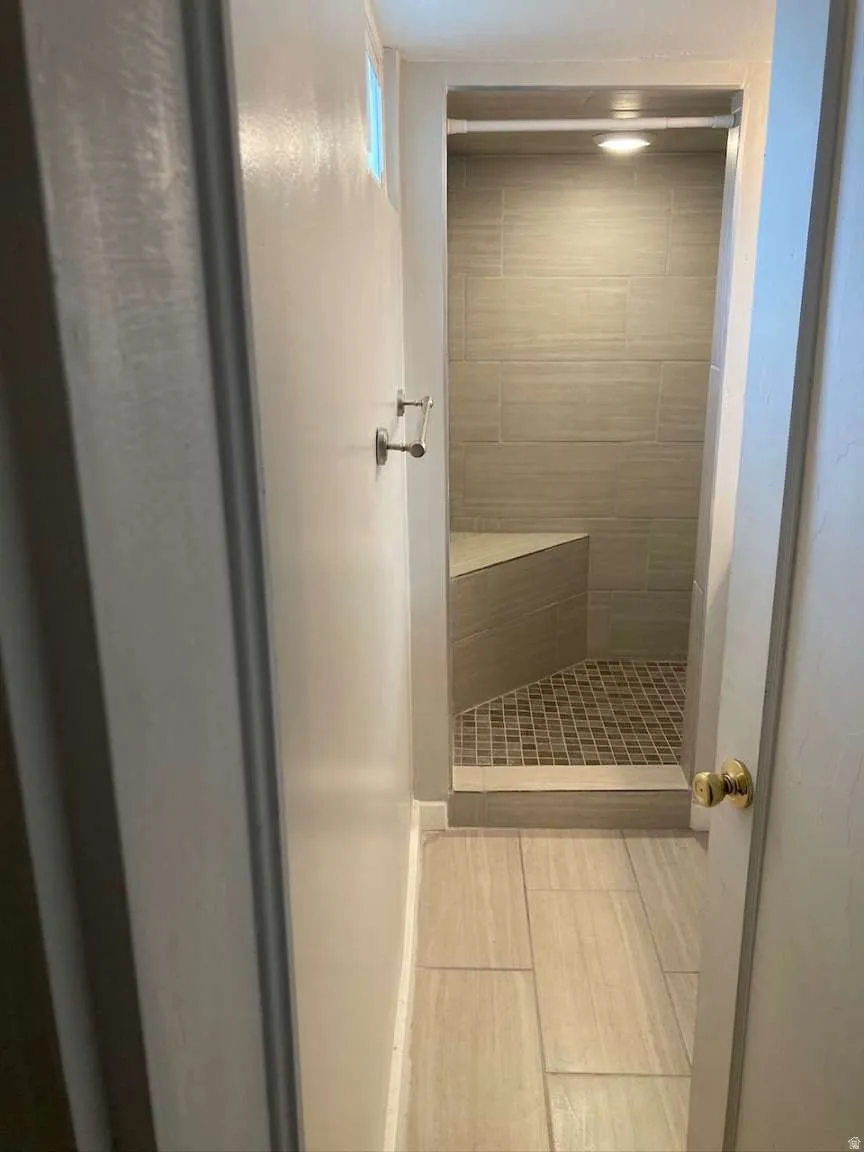 Tiled shower stall featuring a built-in bench, mosaic tile flooring, and integrated lighting