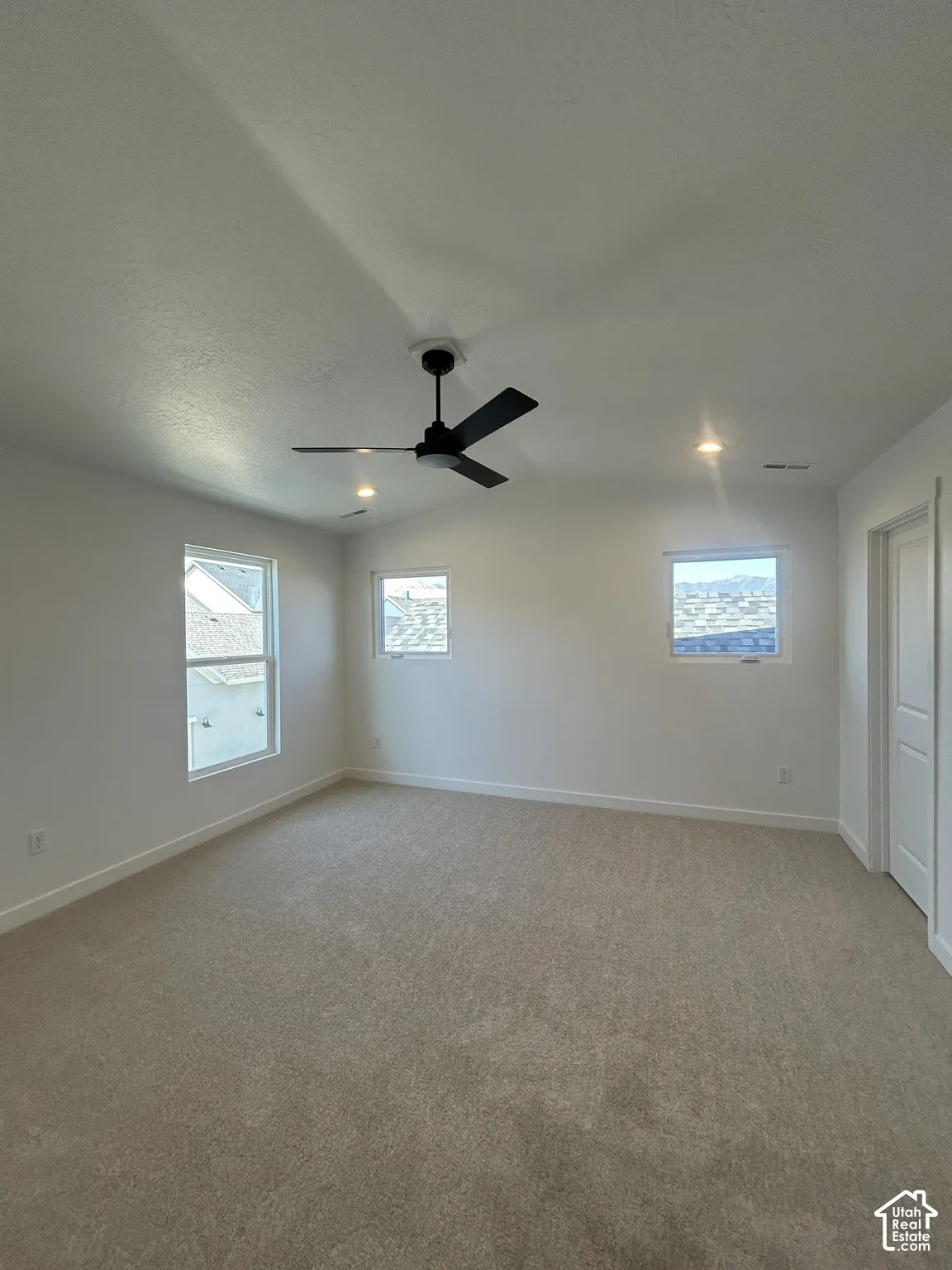 Neutral tone carpet flooring, white painted walls, recessed ceiling lights, and a ceiling fan with integrated lighting