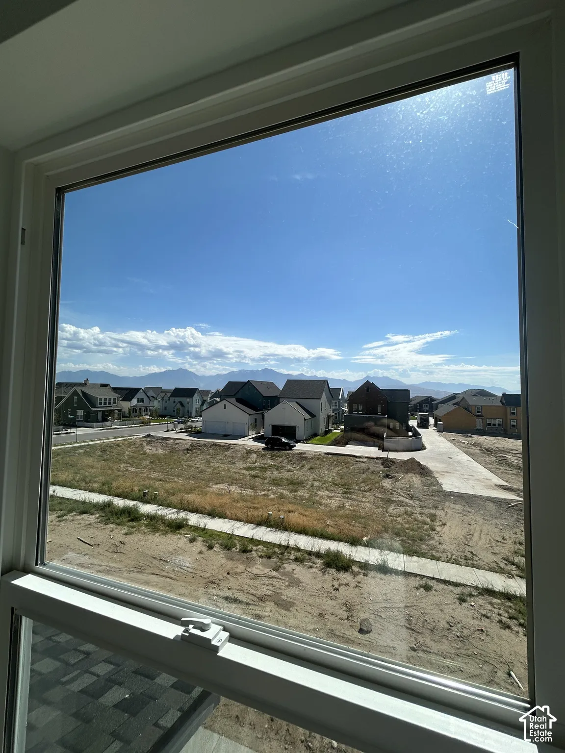 Window with white frame and hardware, showcasing a distant mountain range and neighborhood residences