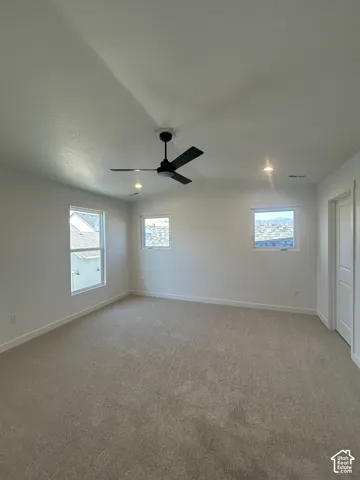 Neutral tone carpet flooring, white painted walls, recessed ceiling lights, and a ceiling fan with integrated lighting