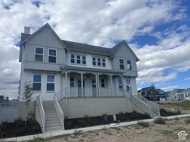 Two-story exterior featuring a mix of vertical board-and-batten and smooth-finish siding, a covered front porch with railing, dual staircases, and multi-pane windows