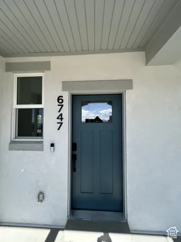 Contemporary entry door with transom window, stucco exterior, and horizontal paneling on the porch ceiling