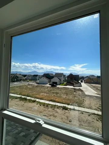 Window with white frame and hardware, showcasing a distant mountain range and neighborhood residences