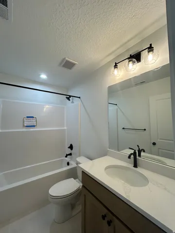 Modern vanity with a light-toned countertop, oval undermount sink, and matte black faucet