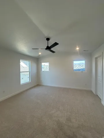Neutral tone carpet flooring, white painted walls, recessed ceiling lights, and a ceiling fan with integrated lighting