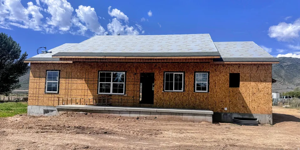New construction featuring a prepared roof, plywood sheathing, multiple windows, and a concrete foundation