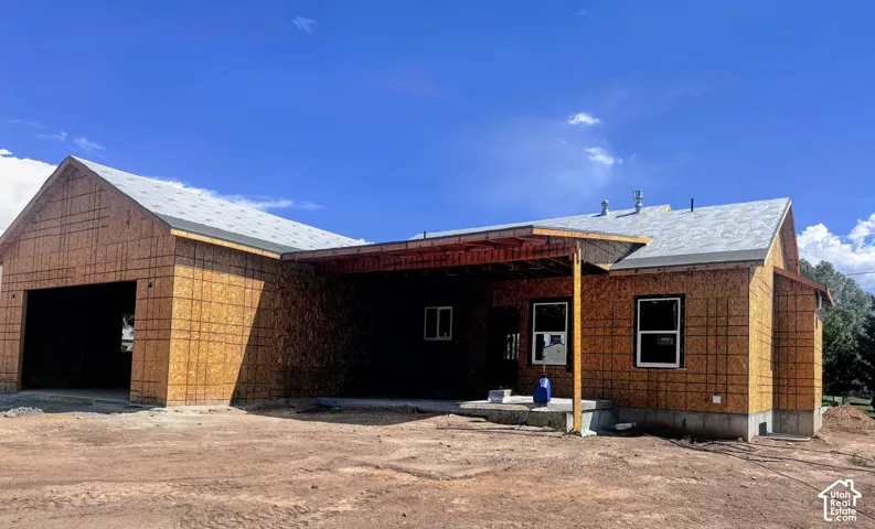 New construction framing with an attached two-car garage, covered patio structure, and multiple windows
