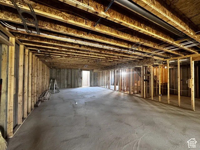 Unfinished basement with exposed ceiling joists, wood framing, and a concrete slab floor