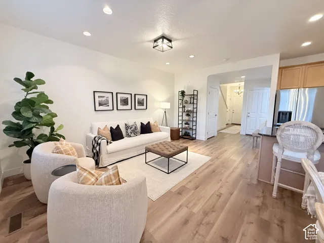 Recessed ceiling lighting, wood-finish flooring, and a contemporary ceiling fixture enhance this living space