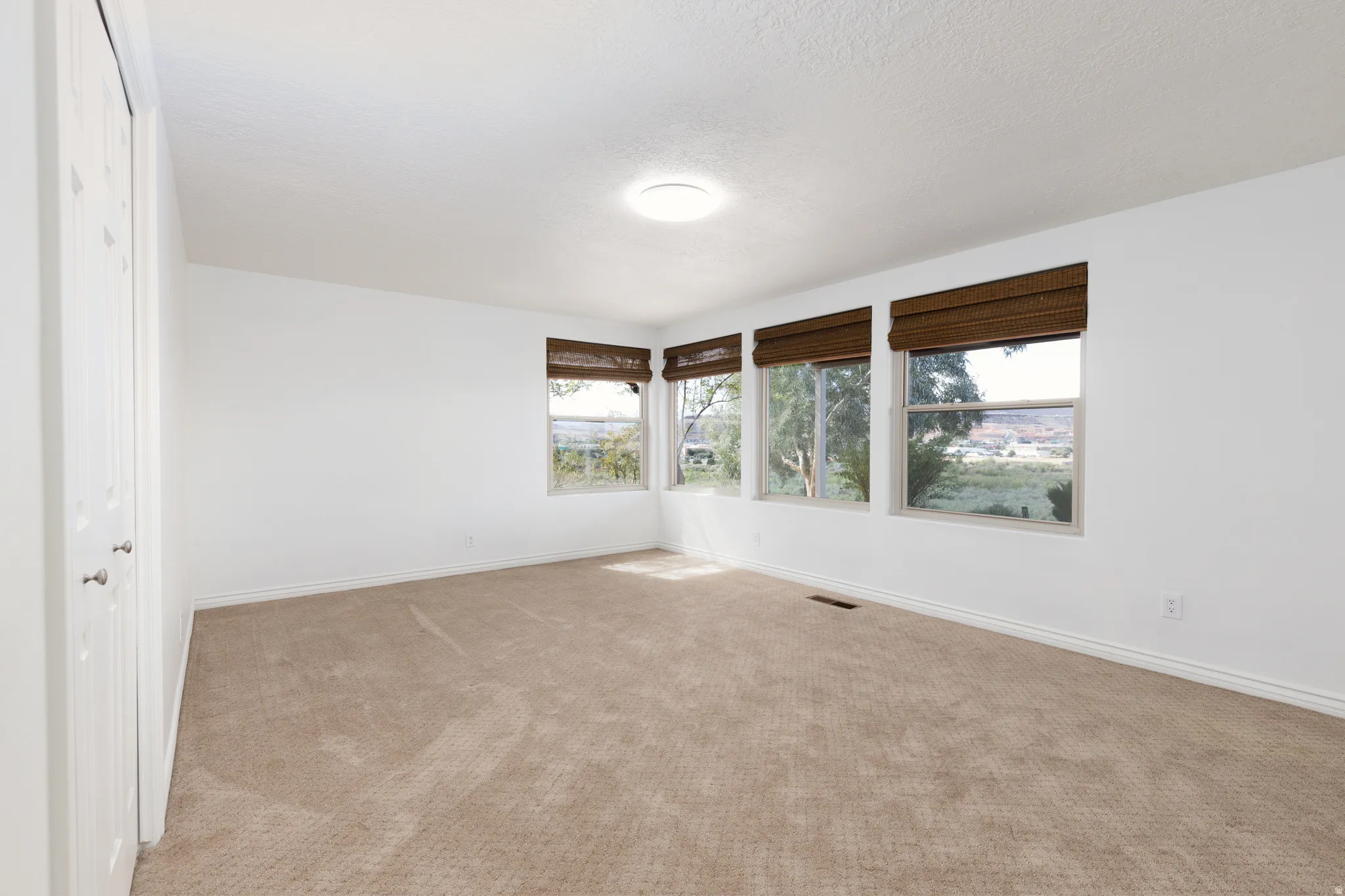 Bedroom 4 Wall-to-wall carpeting and three windows with woven shades