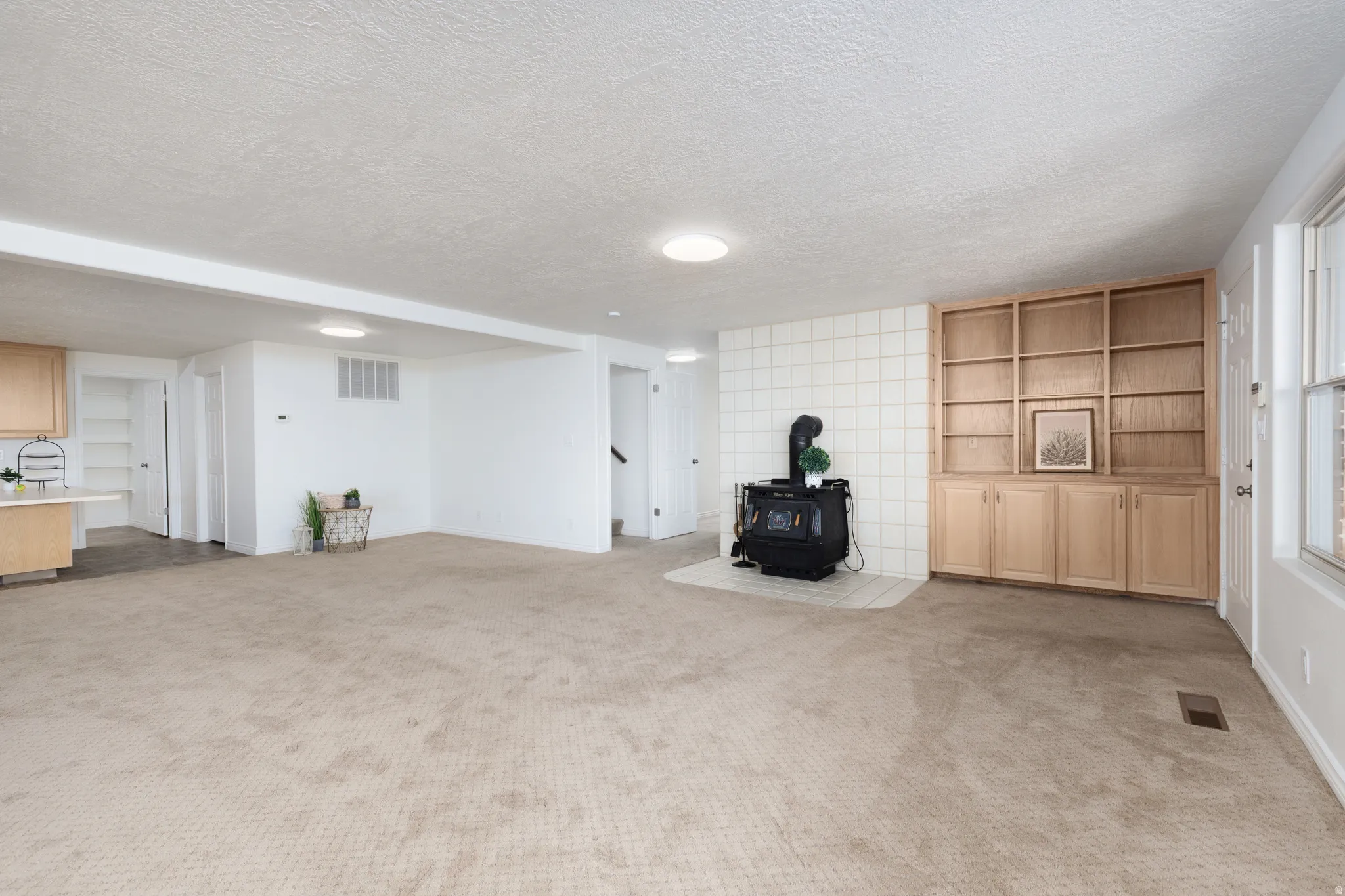 Spacious living area featuring carpet flooring, built-in shelving, a freestanding stove, and recessed lighting