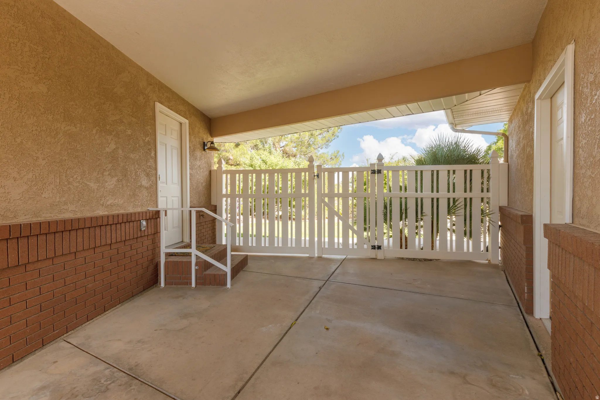 Covered breezeway to garage and a white picket gate
