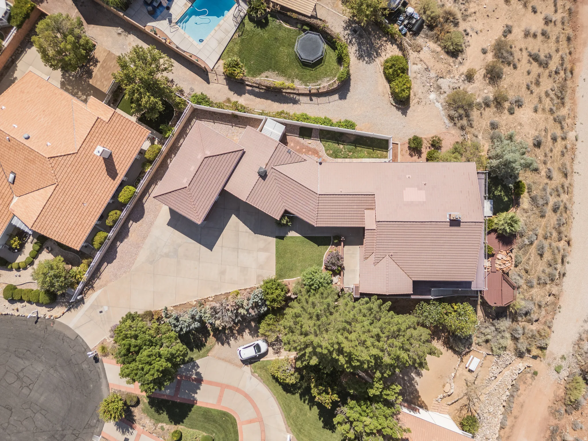 Aerial perspective highlighting property layout with a multi-level roofline, extensive paved driveway, and mature landscaping