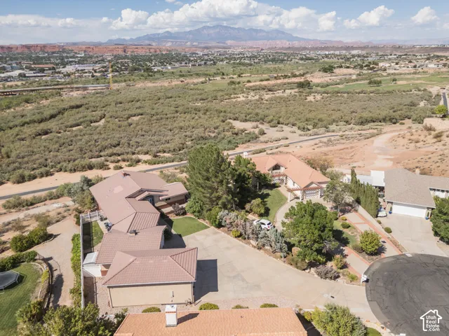 Expansive property on an elevated lot with a mountain backdrop, mature landscaping, and a curvilinear driveway