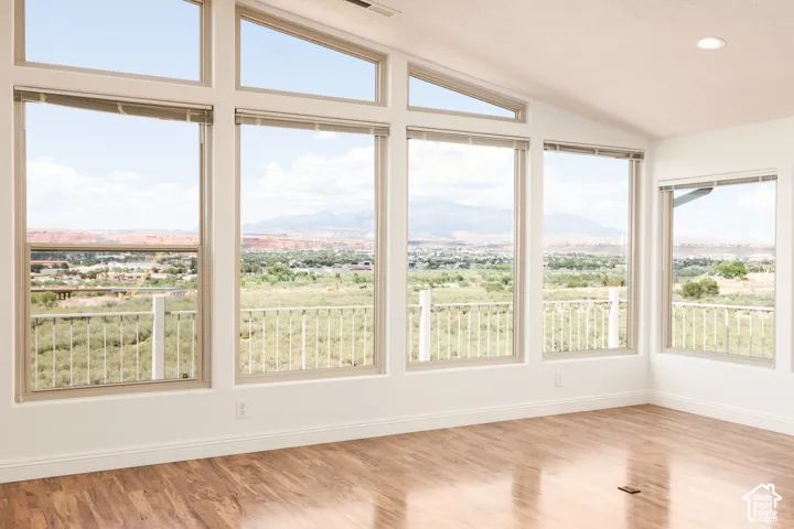 Expansive windows with mountain scenery, vaulted ceiling, recessed lighting, and wood-finish flooring