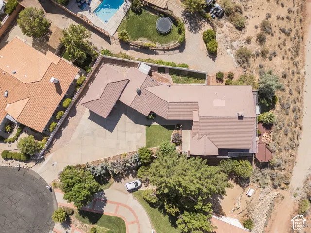 Aerial perspective highlighting property layout with a multi-level roofline, extensive paved driveway, and mature landscaping