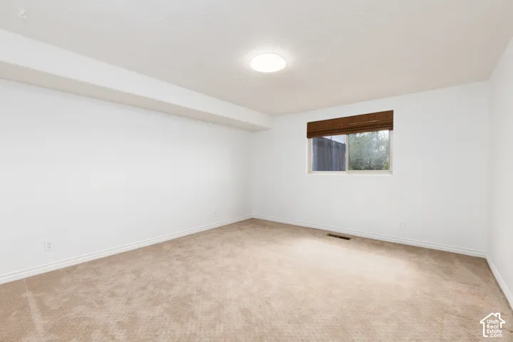 Bedroom 5 Neutral tone wall finish, plush carpeting, recessed lighting, and a single window with a woven shade