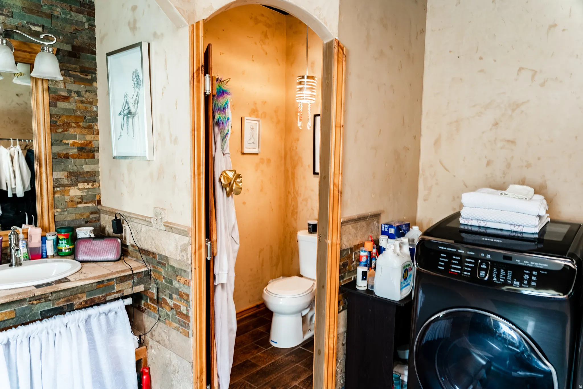 Vanity with natural stone tile surround, integrated sink, and dual-light fixture